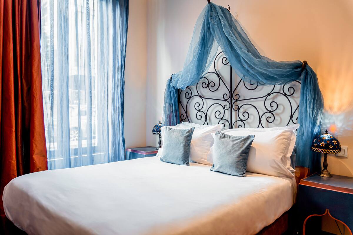A bed with a canopy, two bedside tables, and a lamp.