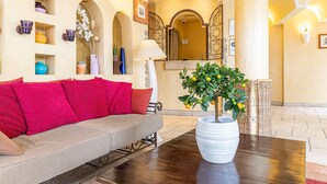 A cozy living area with a sofa, a table with a potted plant, and a decorative mirror. - Villa Royale Montsouris (Paris)