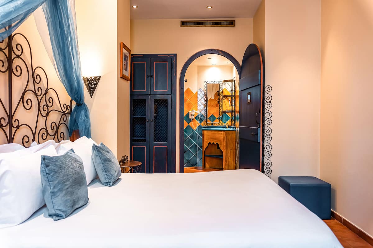 A bedroom with a bed, a nightstand, a dresser, and a mirror.