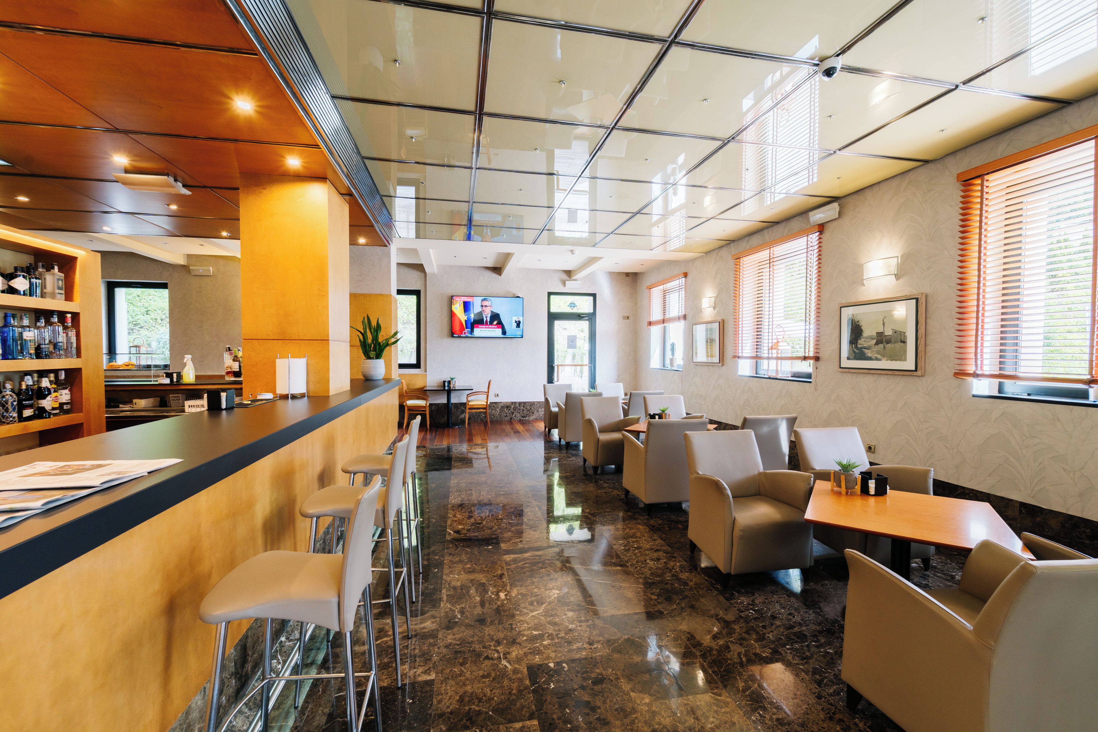 Een moderne hotel lobby met een bar, zitplaatsen en een televisiescherm.