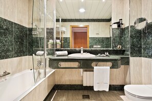 Et moderne badeværelse med et glasafskærmet brusebad, en vask med spejl og et toilet.