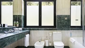 A modern bathroom with a marble countertop, a bidet, a toilet, and a bathtub.