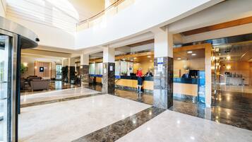 A spacious lobby with a reception desk, seating area, and a staircase leading to an upper level.