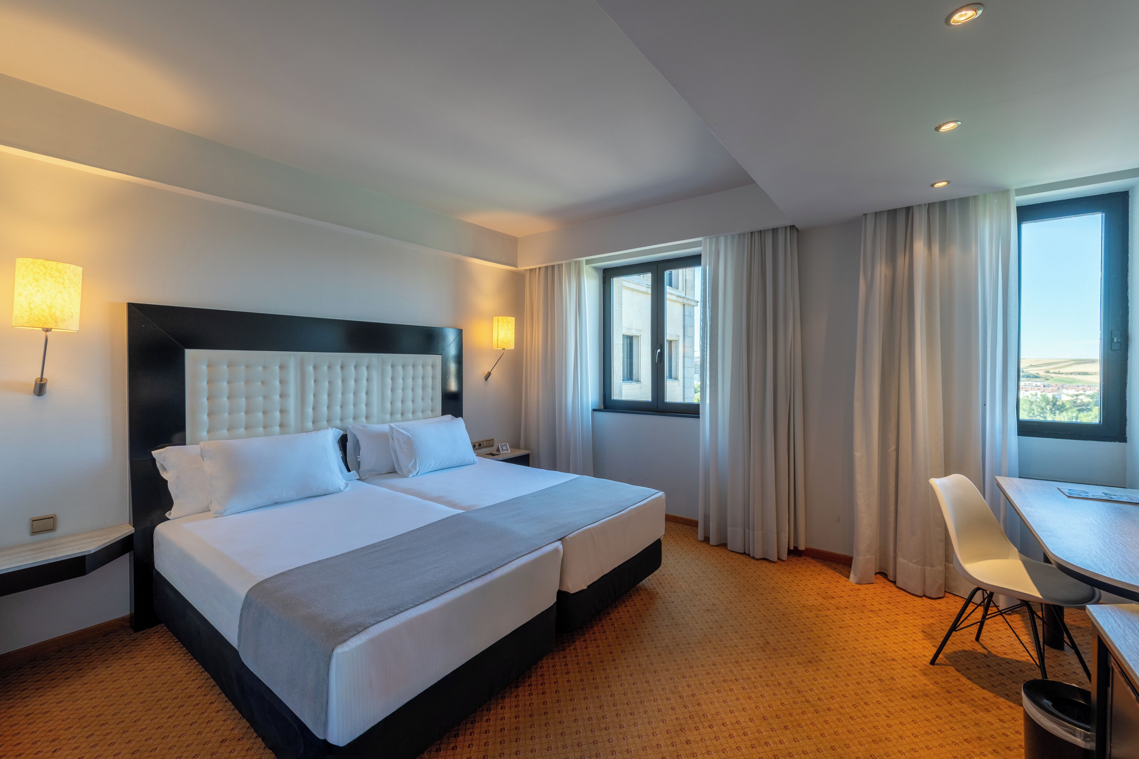 Una habitación de hotel con una cama grande, un escritorio y vistas a la ciudad.