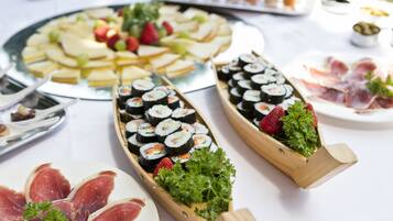 A buffet table with various food items including sushi, fruits, and meats.