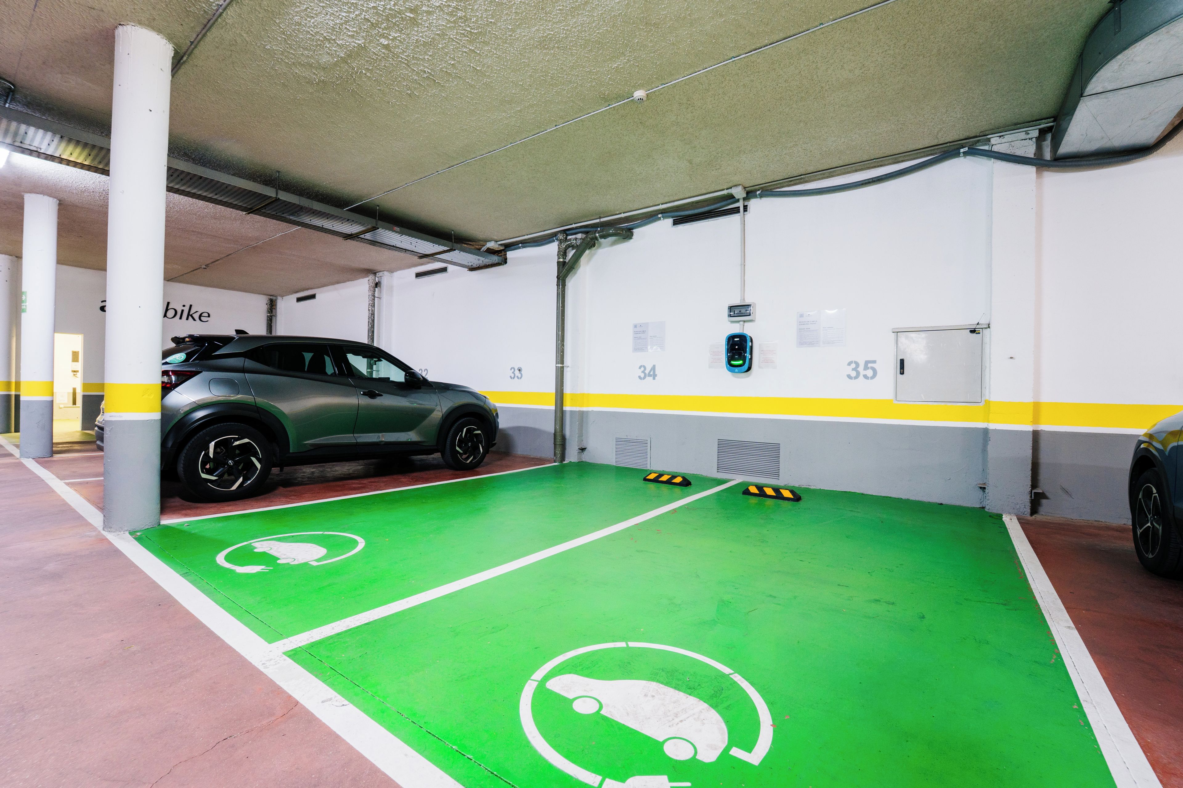 Un garaje de estacionamiento con carriles bici verdes y espacios numerados.