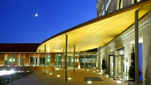Ein Hotel mit überdachter Eingangsbereich, Glasüren und Blumentöpfen.