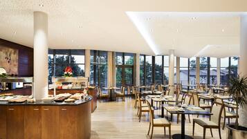 A spacious dining area with high ceilings, large windows, and a central buffet.