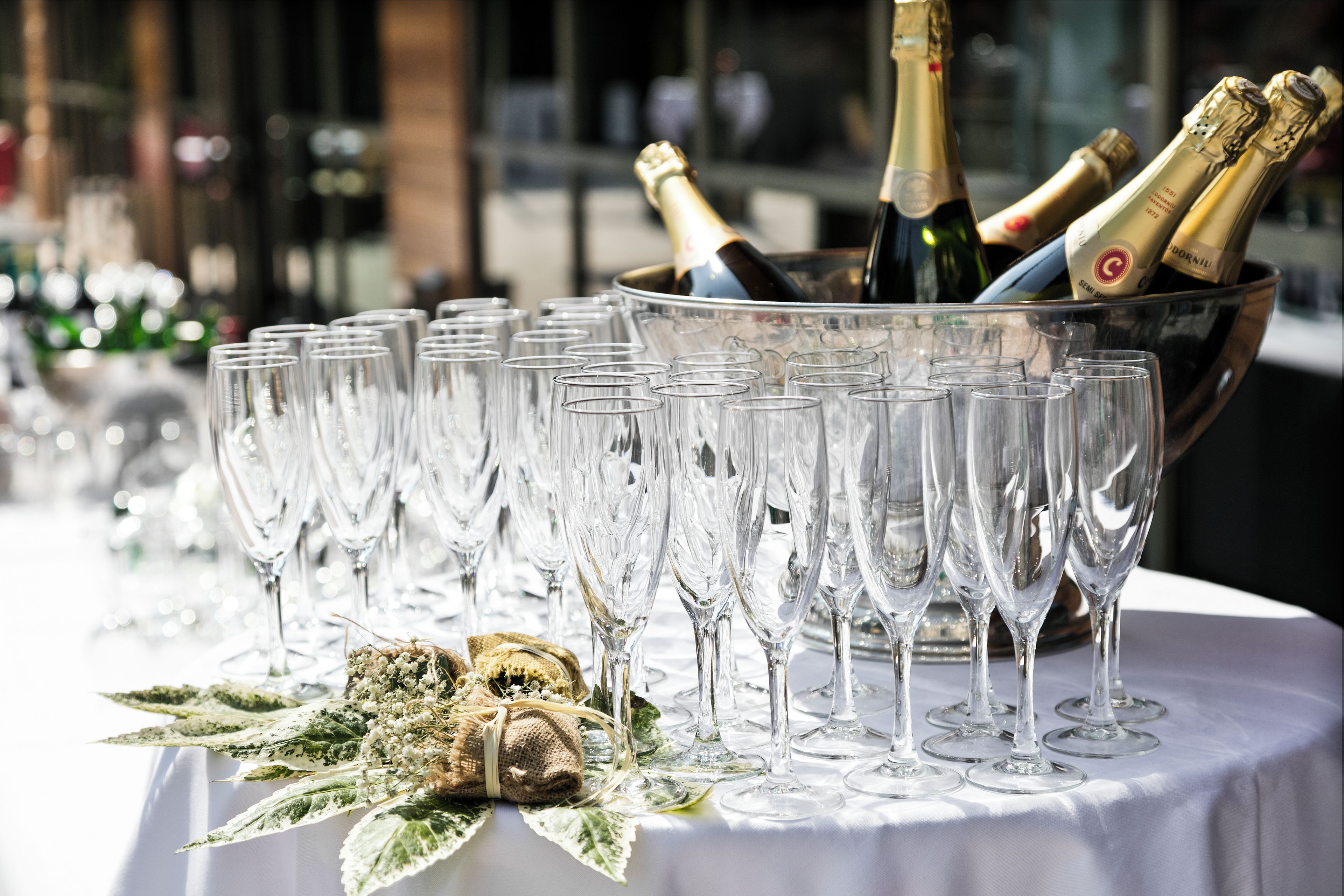A table with multiple champagne flutes and a bucket containing champagne bottles.