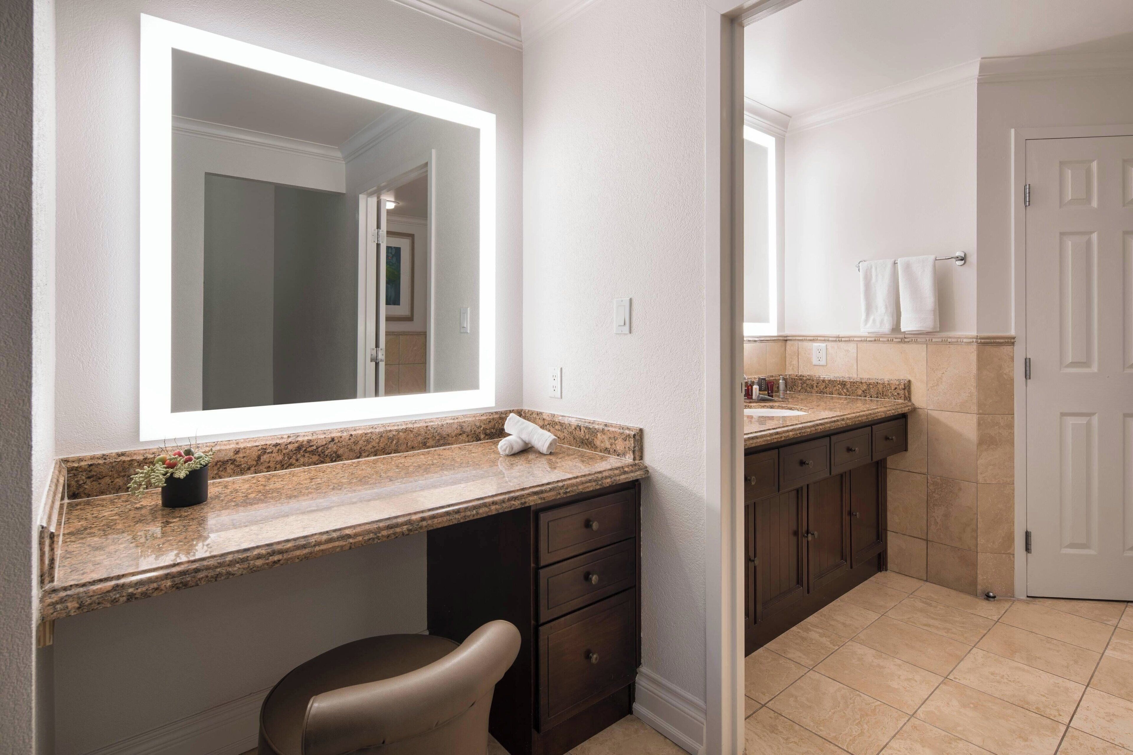 Une salle de bain avec un comptoir en granit, un lavabo, un miroir, un porte-serviettes et une porte.