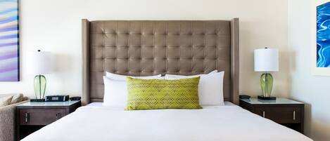 A neatly made bed with a tufted headboard, two bedside tables with lamps, and a pillow with a geometric pattern.