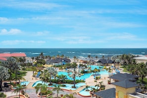 Un resort con varias piscinas, palmeras y vistas al océano.