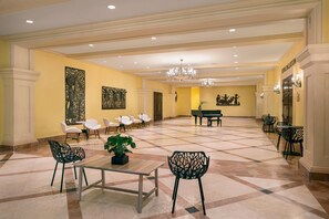A spacious lobby with a piano, seating areas, and artwork on the walls.