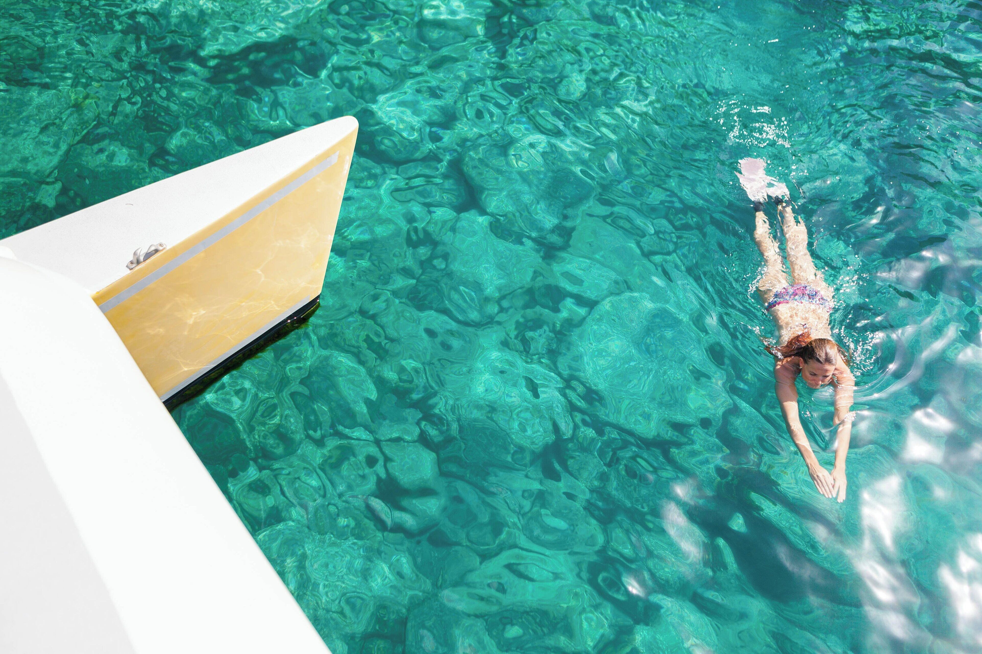 A person swimming in a pool with a boat partially visible.