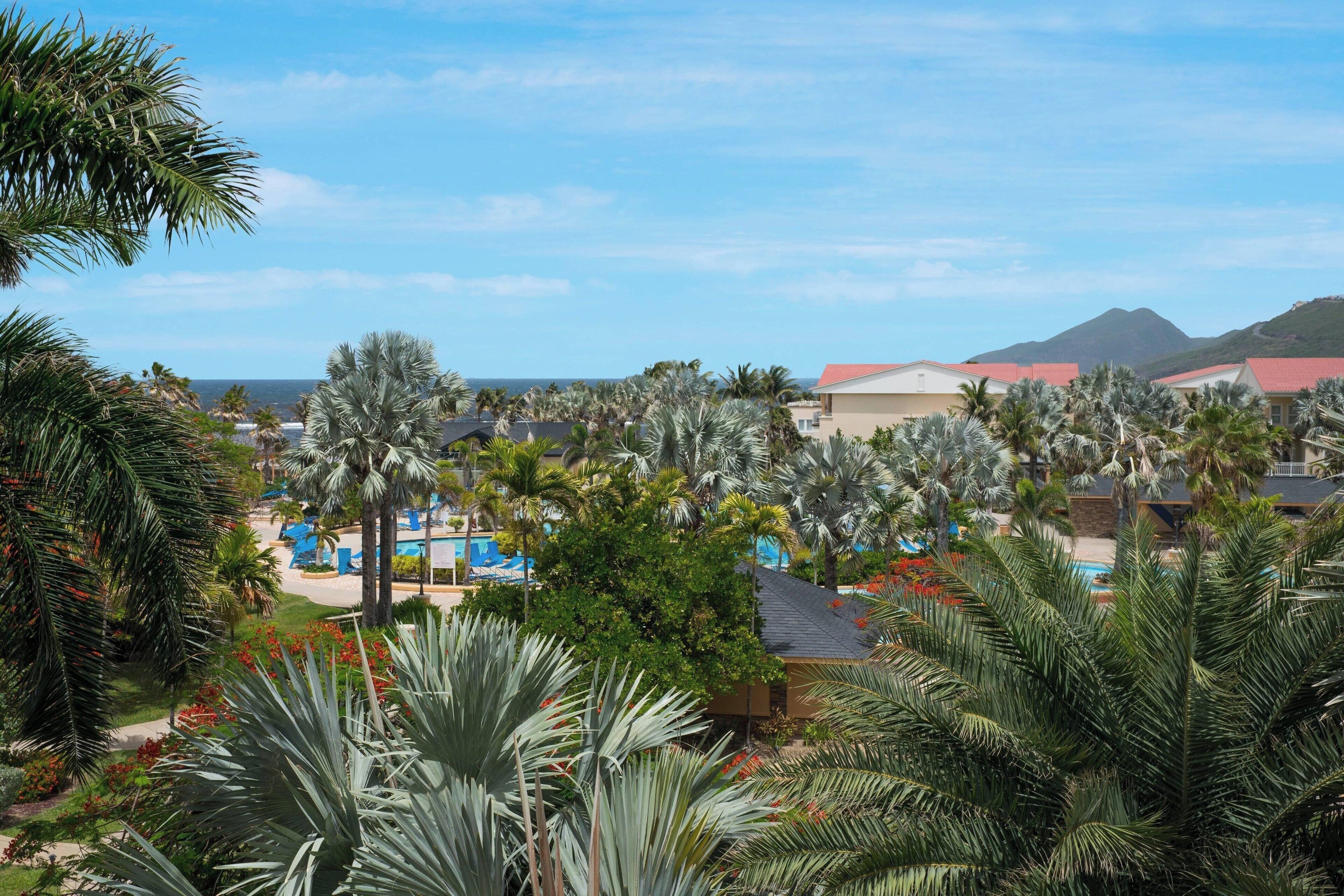 A resort with multiple buildings, palm trees, and a pool area.