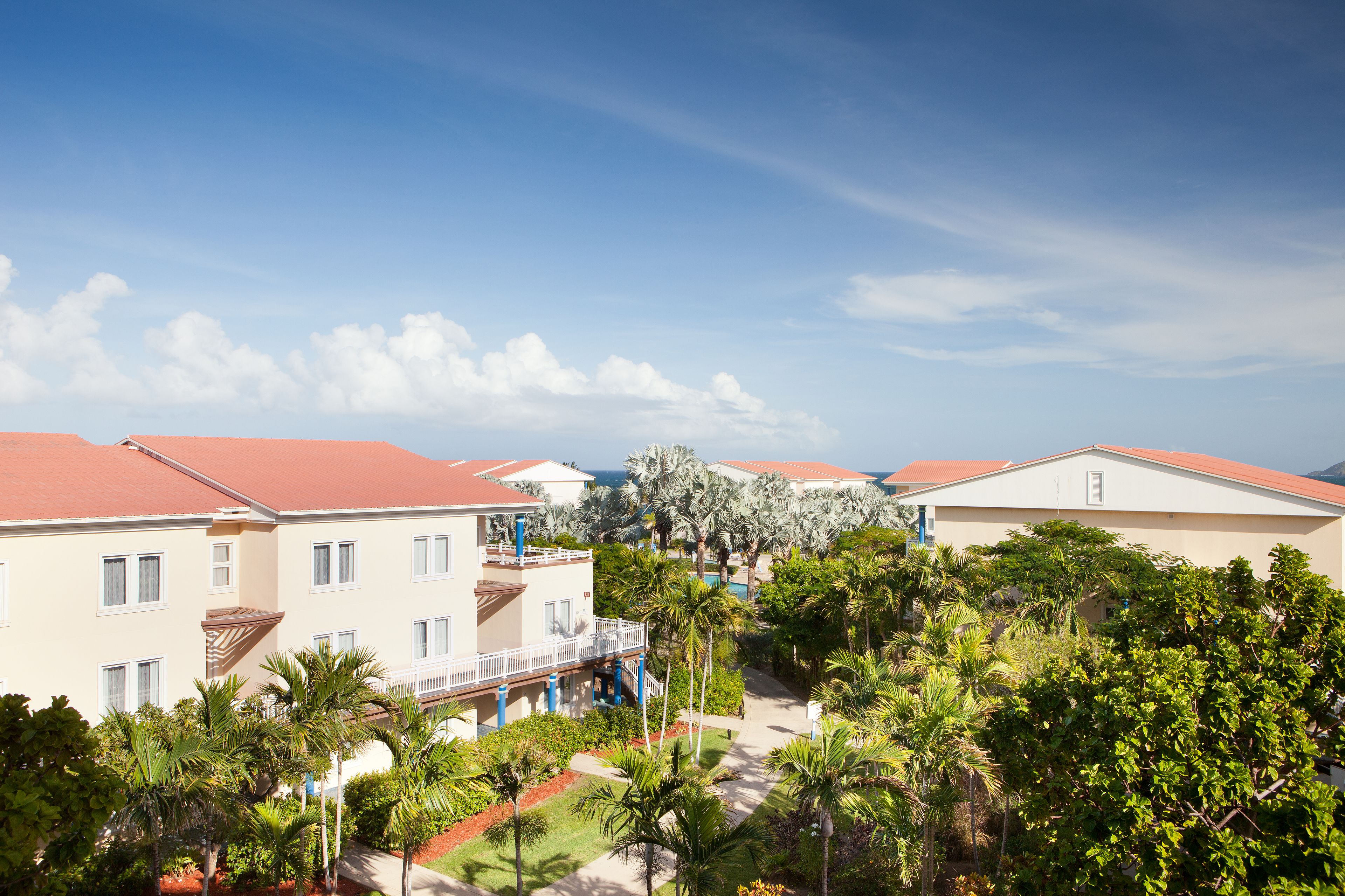 A resort with multiple buildings, palm trees, and a clear sky.