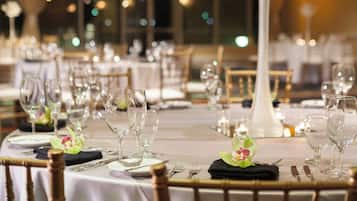 A banquet hall with round tables set for a formal event, featuring white tablecloths, clear glassware, and floral centerpieces.