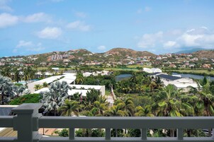 Un resort con varias edificaciones, palmeras y una masa de agua.
