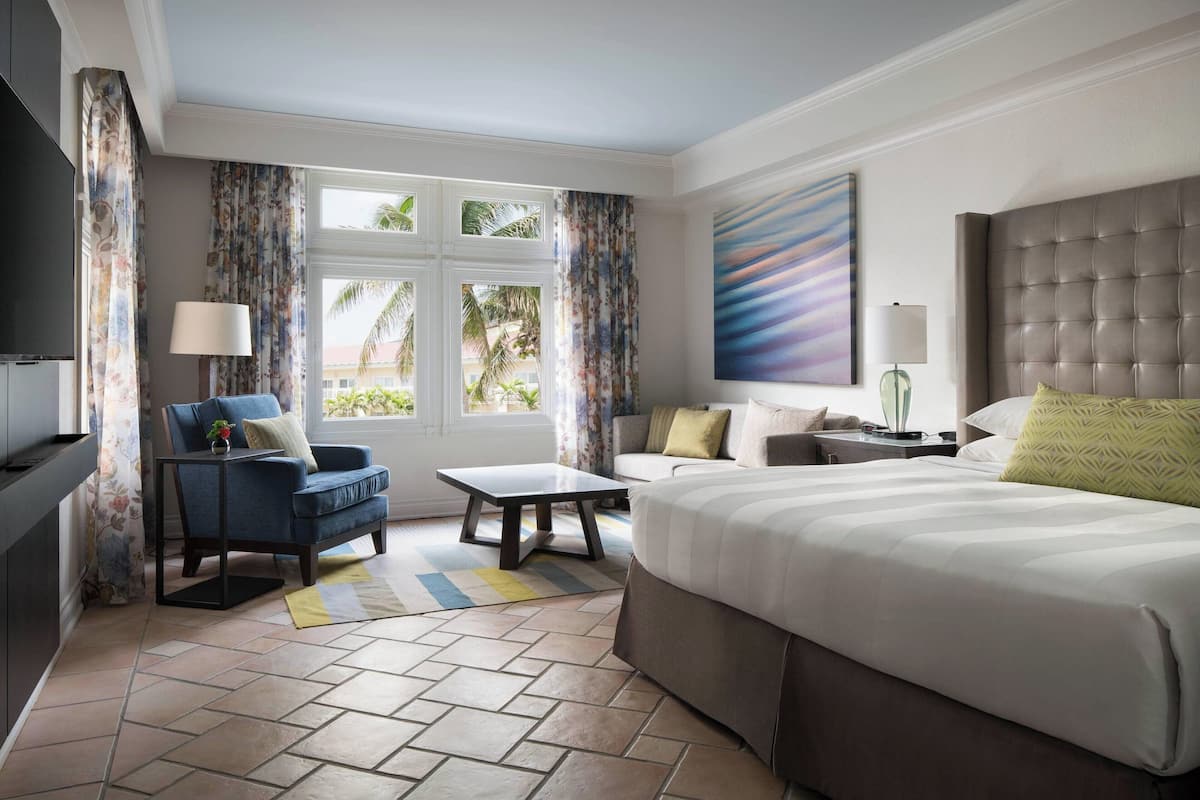 A hotel room with a large bed, a sofa, a coffee table, and a TV.