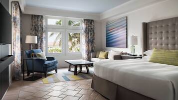 A hotel room with a large bed, a sofa, a coffee table, and a TV.