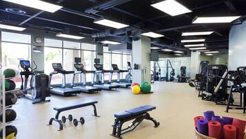 A gym with treadmills, elliptical machines, free weights, and exercise balls.