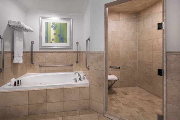 Un baño moderno con bañera, cabina de ducha y barras de apoyo.