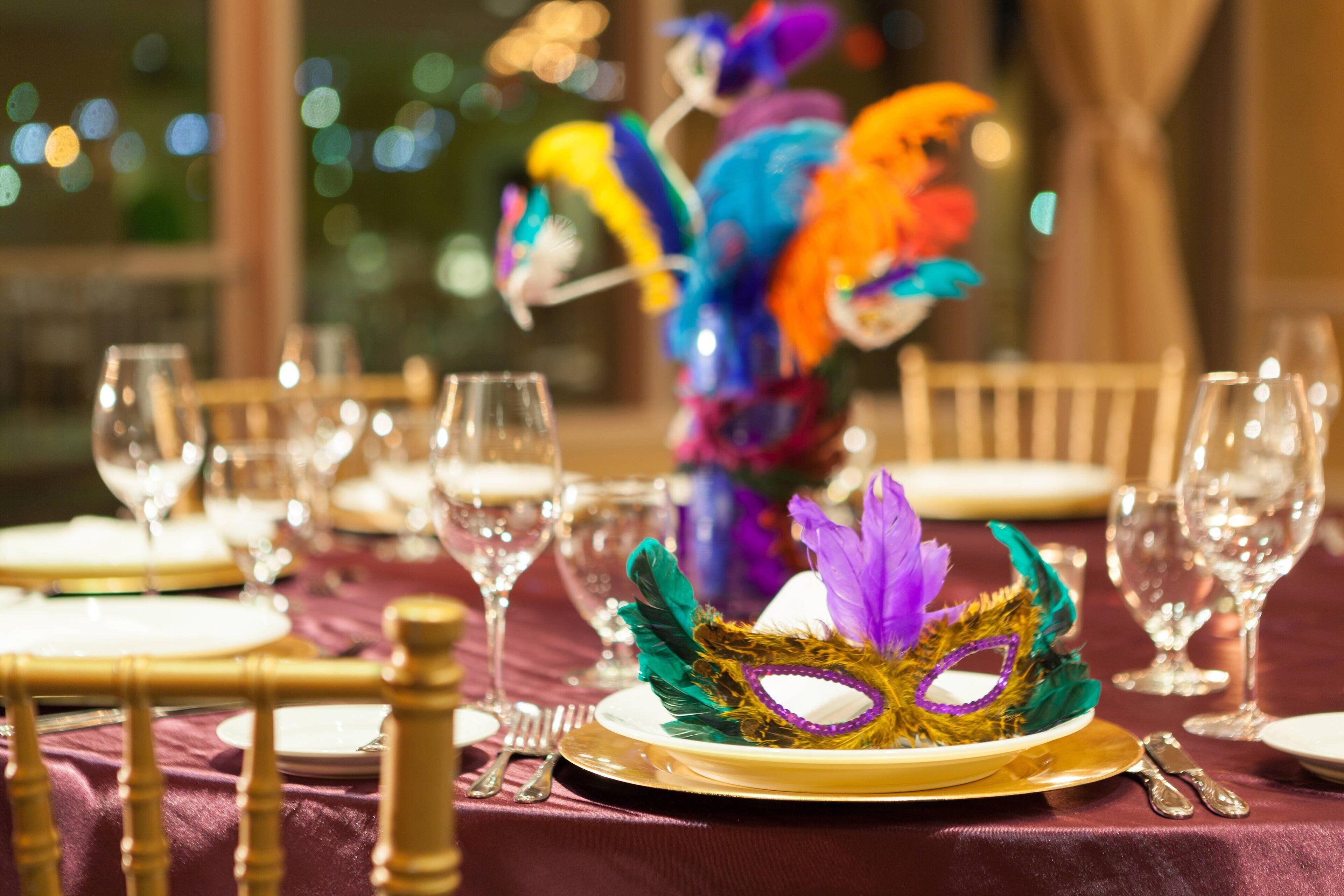 A table set for a meal with a decorative mask centerpiece.