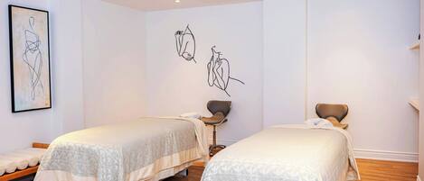 Une chambre avec deux lits, une chaise et des œuvres d’art murales.