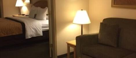 Une chambre d’hôtel avec un lit, un canapé, une table basse et une lampe.