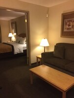 A hotel room with a bed, a sofa, a coffee table, and a lamp.