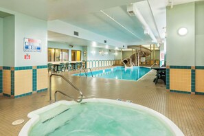 An indoor swimming pool with a lifeguard station, lounge area, and a hot tub.