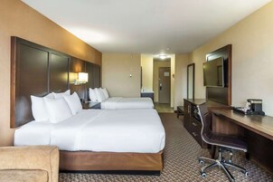 A hotel room with two beds, a desk, a chair, a mirror, and a TV.