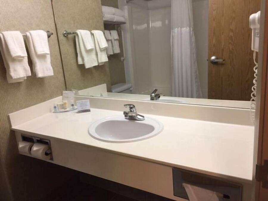 A bathroom with a sink, mirror, and towel rack.