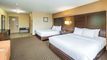 Ett hotellrum med två sängar, ett skrivbord, en stol och ett golv täckt av matta.