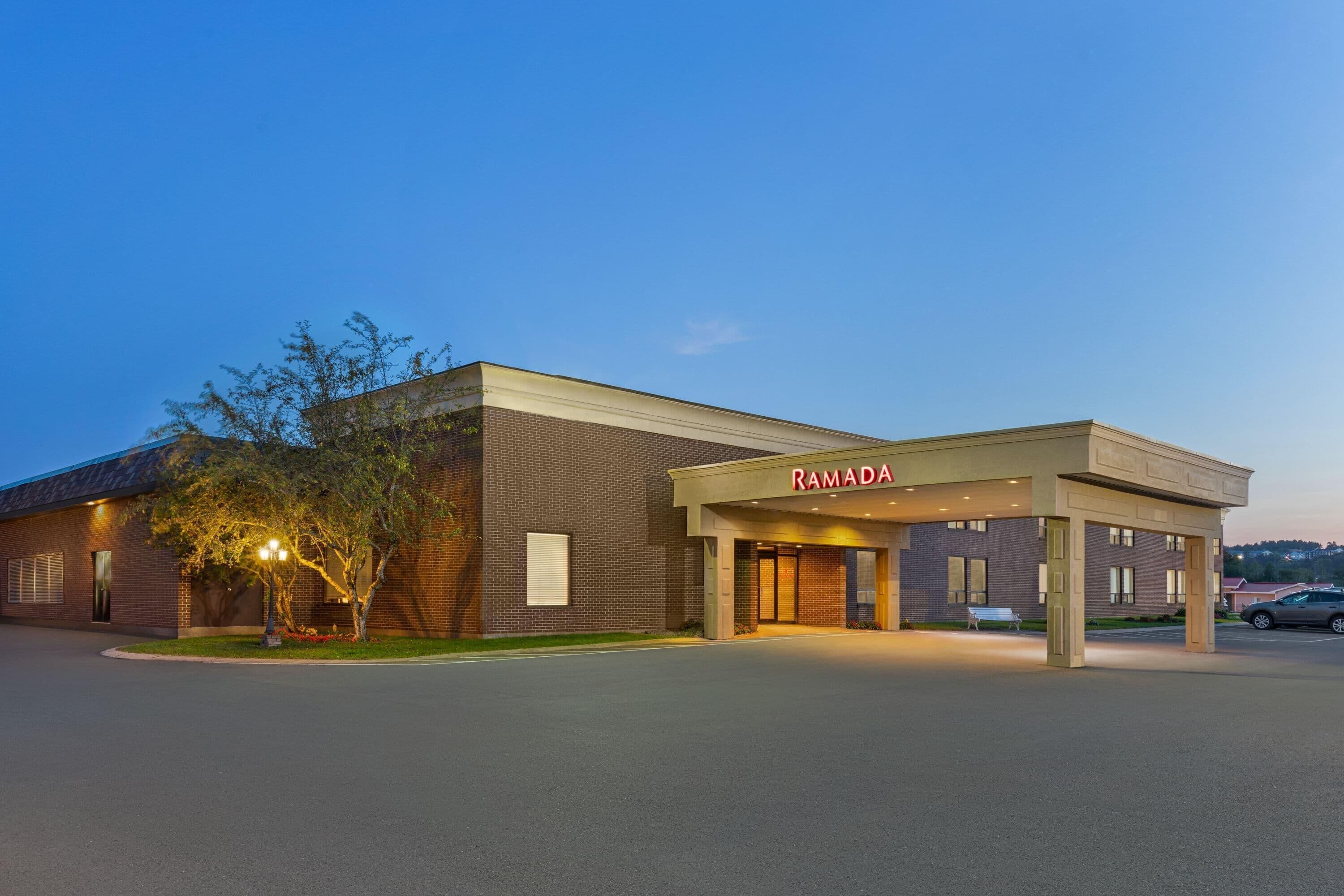 Een gebouw met een bord waarop 'RAMADA' staat, wat aangeeft dat het een hotel is.