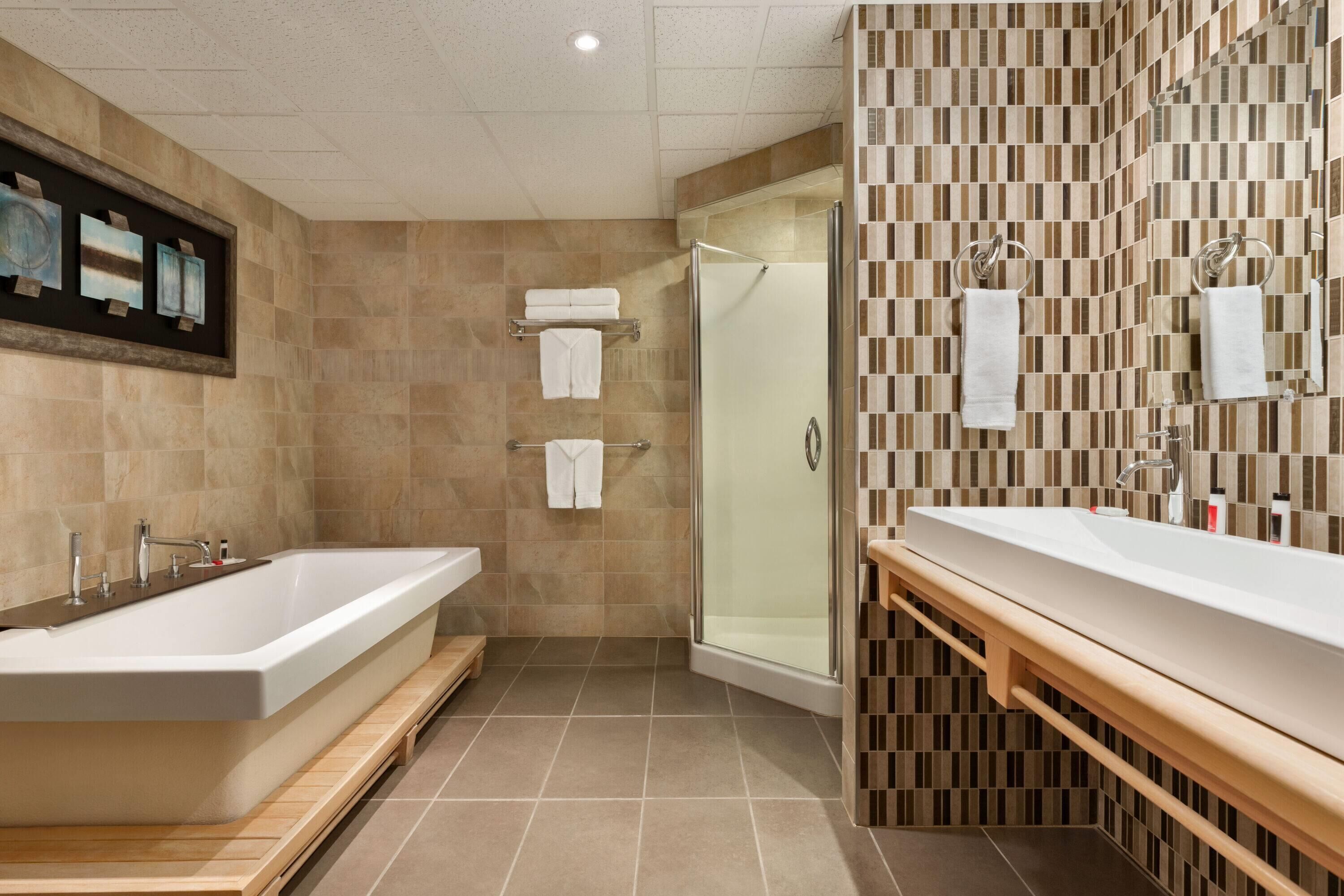 Une salle de bain moderne dotée d’une grande baignoire, d’une douche séparée et d’un meuble-lavabo avec un miroir.