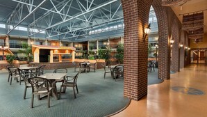 A spacious indoor area with a high ceiling, featuring a central bar area, multiple seating arrangements, and brick columns. - Ramada by Wyndham Fredericton (Fredericton)