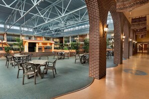 A spacious indoor area with a high ceiling, featuring a central bar area, multiple seating arrangements, and brick columns. - Ramada by Wyndham Fredericton (Fredericton)