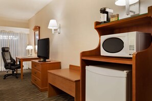 A hotel room with a desk, chair, television, microwave, and refrigerator. - Ramada by Wyndham Fredericton (Fredericton)