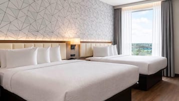 A hotel room with two beds, a geometric patterned wall, a large window with curtains, and a view of the outdoors.