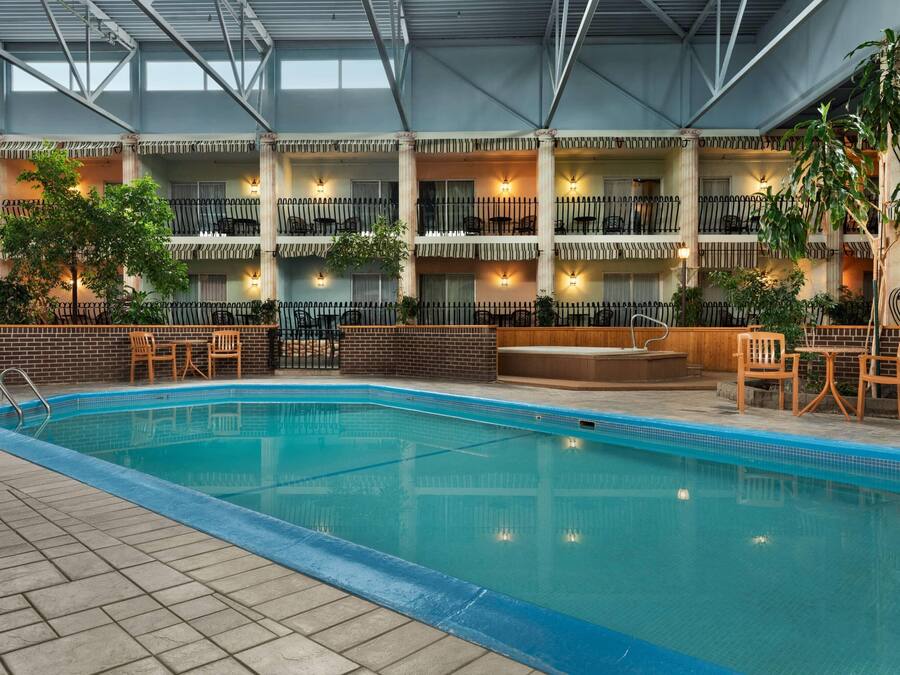 An indoor swimming pool with multiple levels of balconies, each with seating and potted plants.