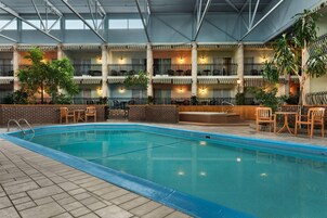 Una piscina interior con varios niveles de balcones, cada uno con asientos y plantas en macetas.