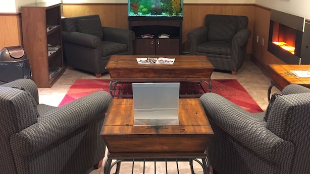 A living room with a large fish tank, two armchairs, a coffee table, and a flat-screen TV. - Ramada by Wyndham Fredericton (Fredericton)