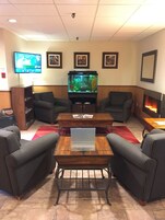 Una sala de estar con un acuario grande, dos sillones, una mesa de centro y un televisor de pantalla plana.