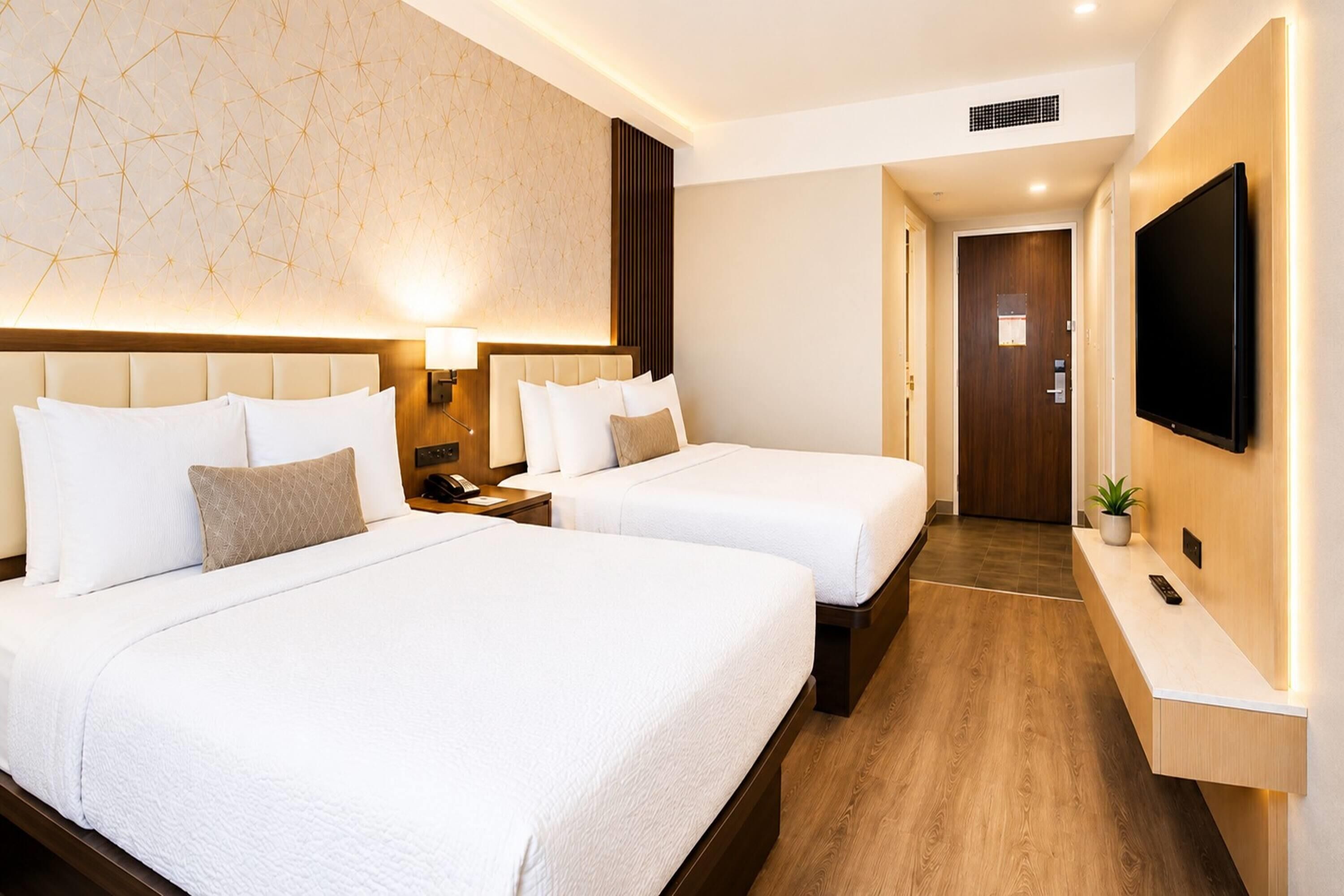 Una habitación de hotel con dos camas, televisión, escritorio y puerta de baño.