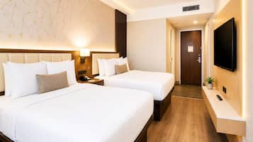 A hotel room with two beds, a TV, a desk, and a bathroom door.