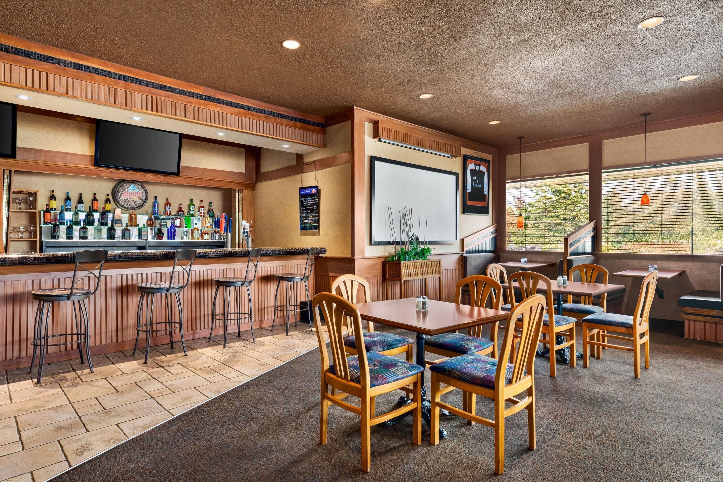 A bar area with a variety of liquor bottles, a flat-screen TV, and a chalkboard menu.
