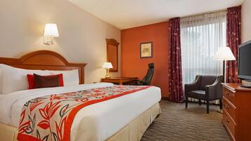 A hotel room with a large bed, a desk, a chair, a television, and a window with curtains.