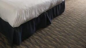 A hotel room with a large bed, a sofa, a small table, and a lamp. - Ramada by Wyndham Fredericton (Fredericton)