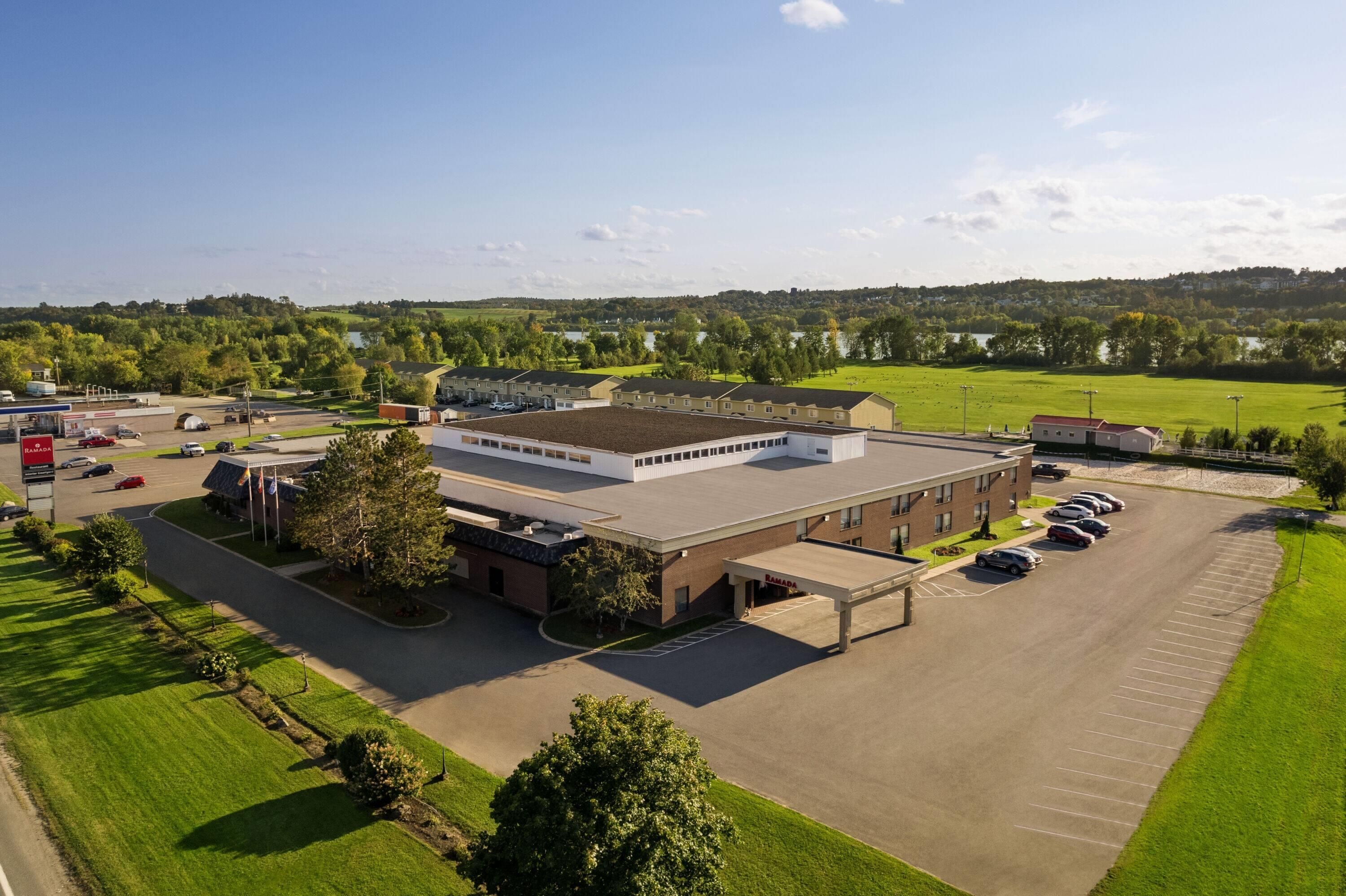 A large building with a parking lot and a green field in the background.
